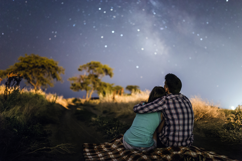 couple en train de s'embrasser en regardant les étoiles