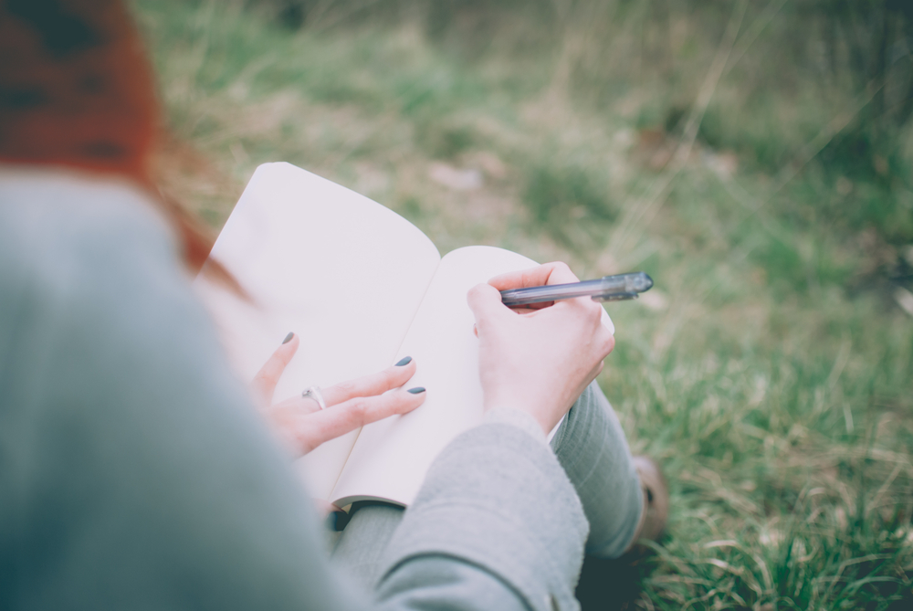 women writing book in the park
