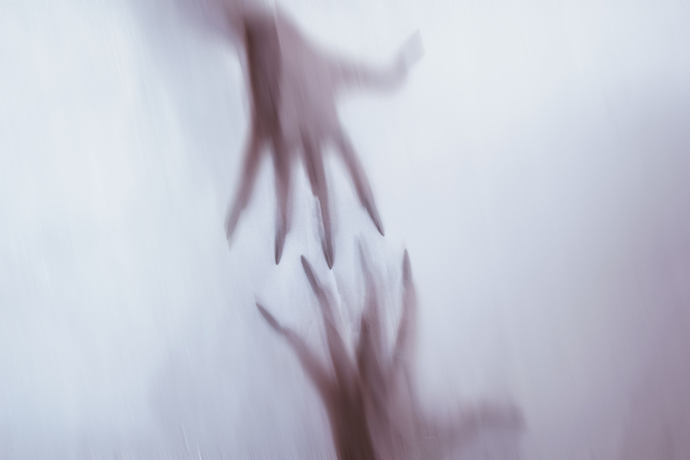 A silhouette of a female figure behind foggy glass. A concept of the spirit of poltergeist from the other world.